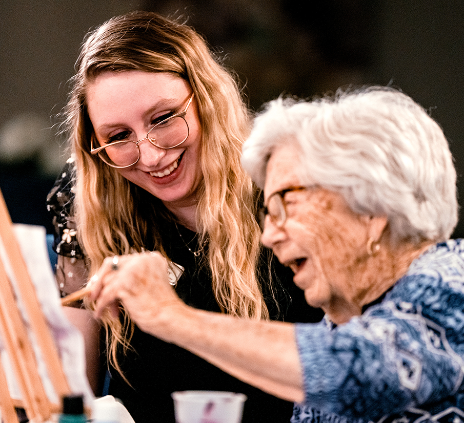 Resident smiling while painting a picture